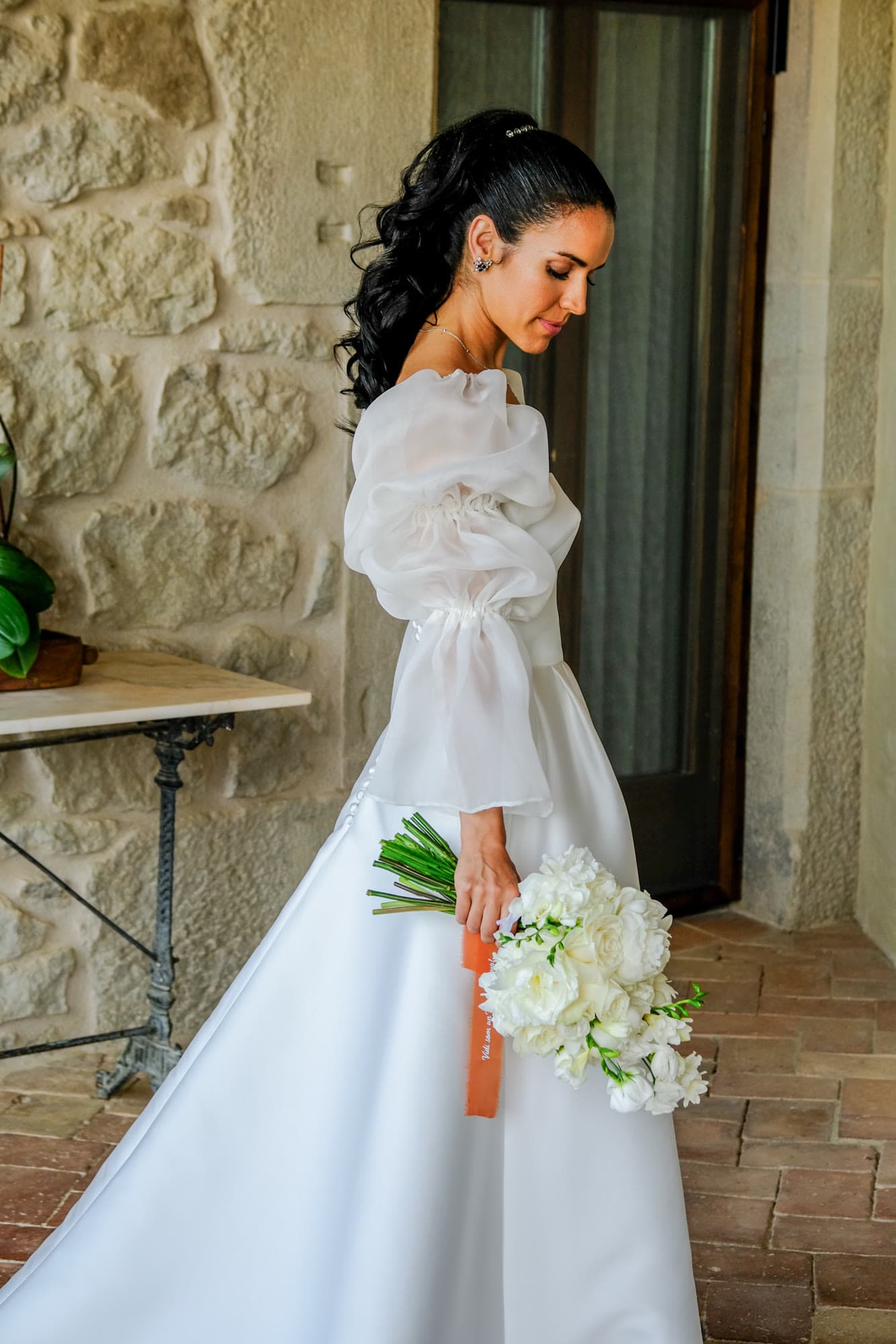 Bride in profile holding a bouquet against a stone wall